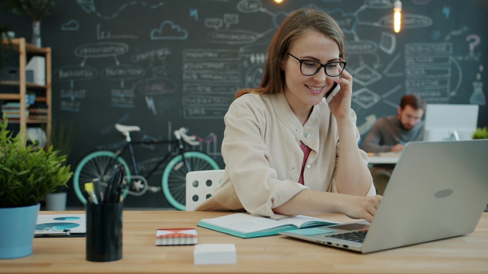An office manager smiling on the phone at her laptop.